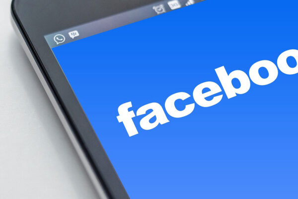 A close-up of a smartphone screen displaying the Facebook logo on a blue background.