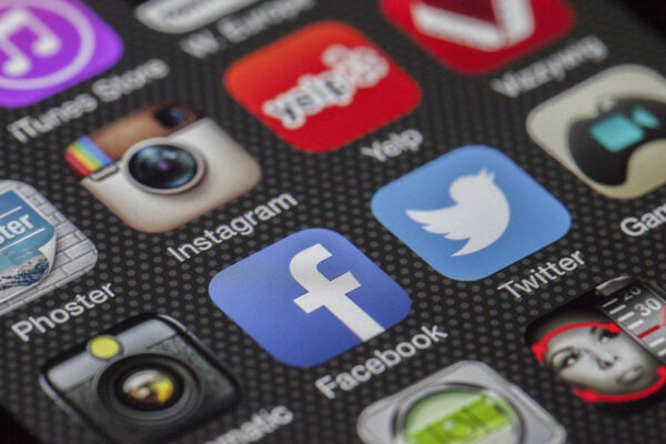Close-up of a smartphone screen displaying various social media and app icons, including Instagram, Facebook, Twitter, Yelp, and YouTube.